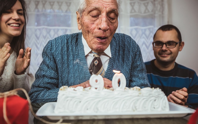 man blowing out candles on 90th birthday cake